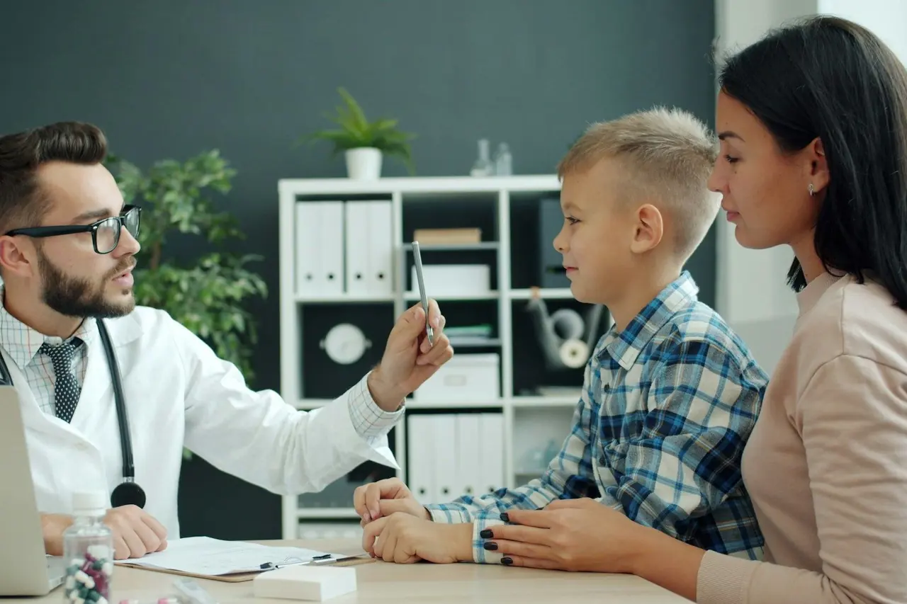 Médico conversando com mãe e filho durante consulta no consultório