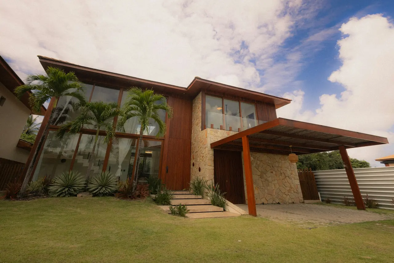 Casa moderna de madeira e pedra com palmeiras e gramado