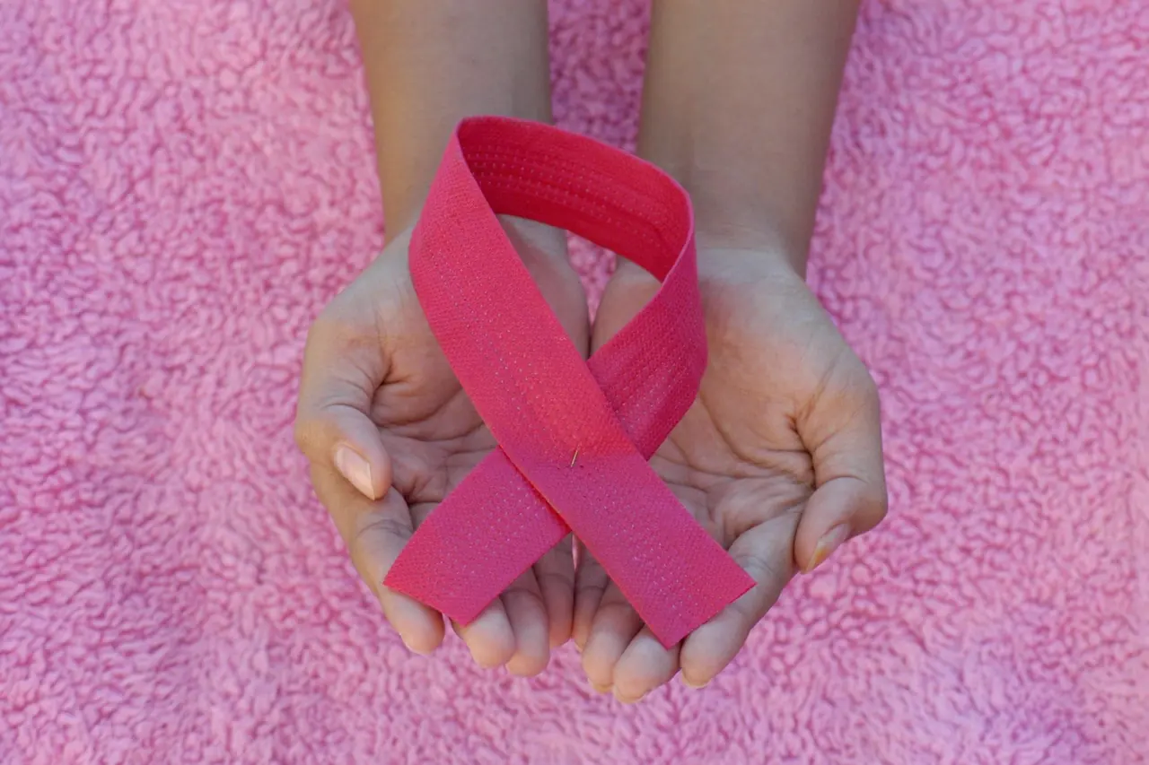Mãos segurando o laço rosa do Outubro Rosa