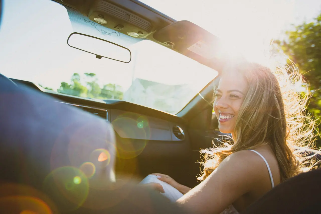 Mulher sorrindo ao volante em um dia de sol