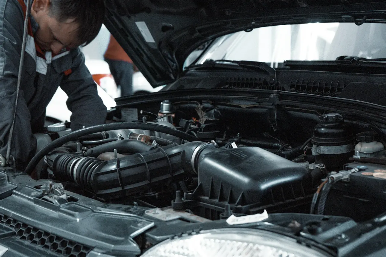 Mecânico inspecionando o motor de um carro na oficina