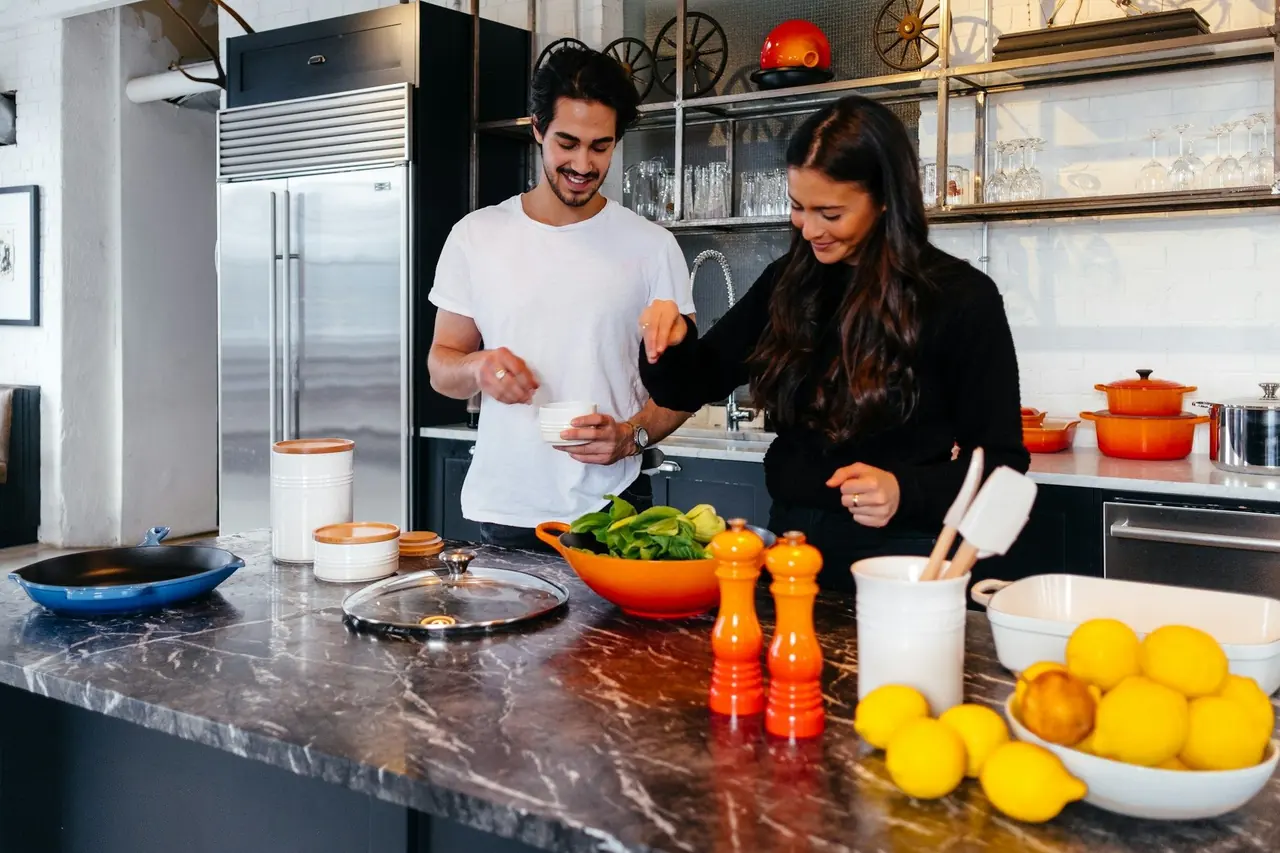 Casal preparando uma refeição saudável com verduras na cozinha