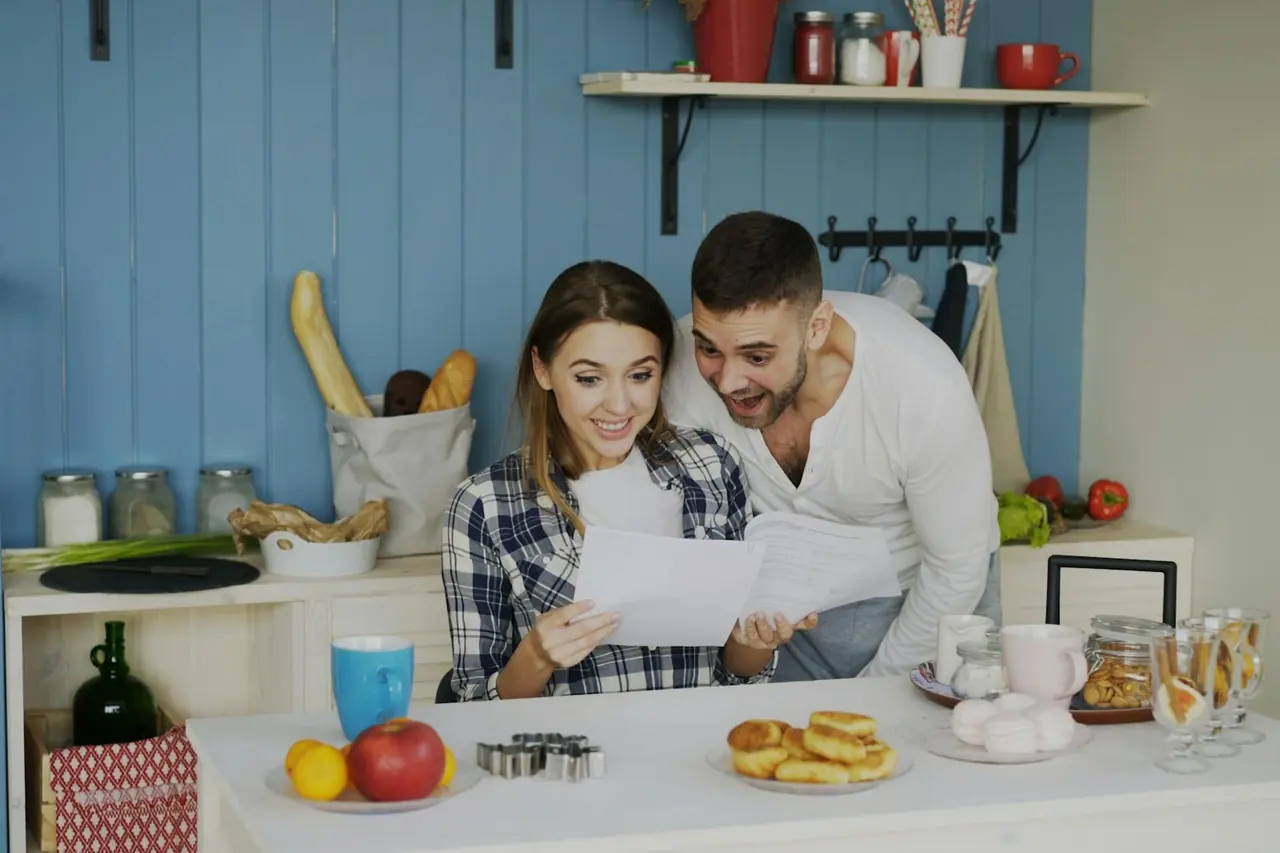 Casal lendo e comparando documentos juntos na cozinha