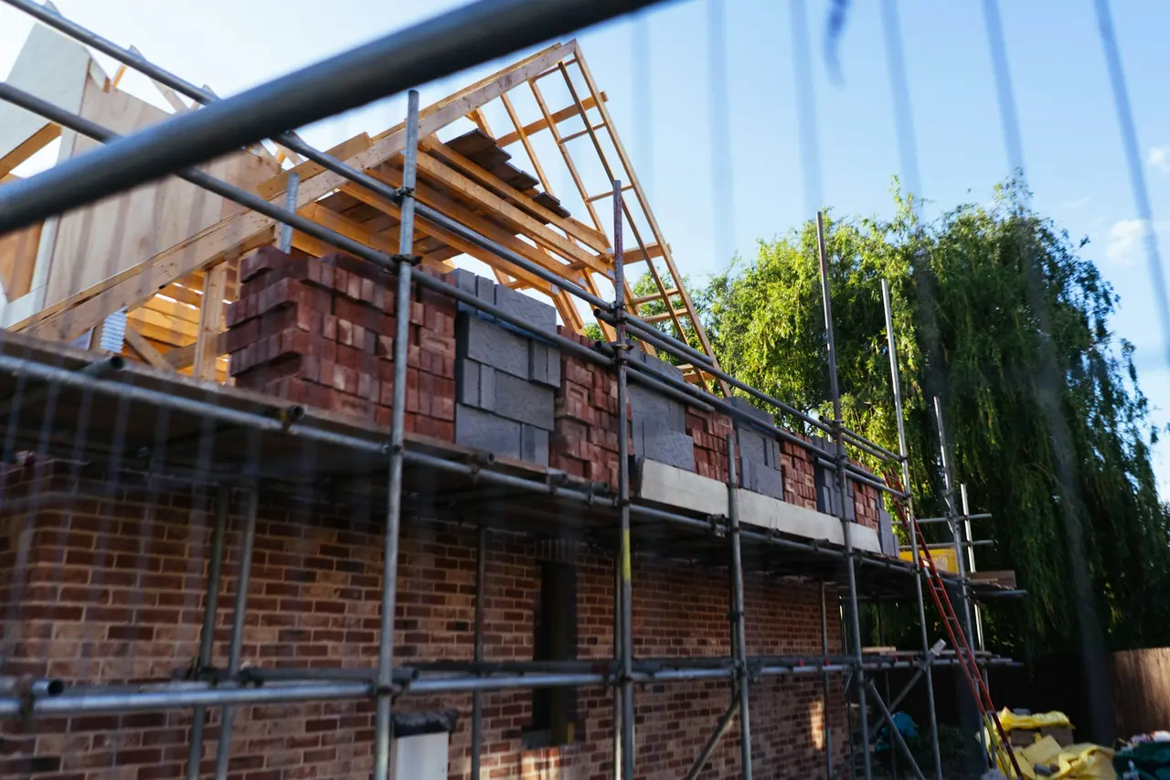 Casa de tijolos em construção com andaimes e telhado de madeira