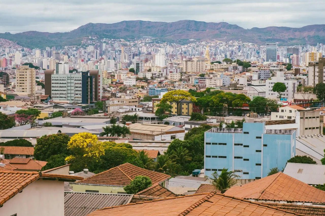 Vista de uma cidade mineira com telhados, prédios e serra ao fundo