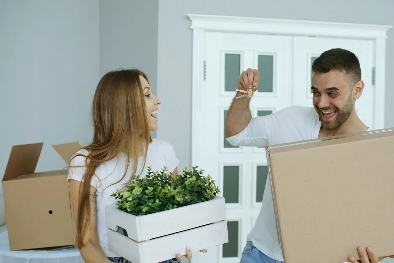 Casal feliz chegando ao novo lar com caixas e as chaves na mão