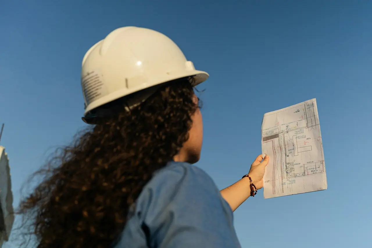 Engenheira de capacete analisando um projeto ao ar livre