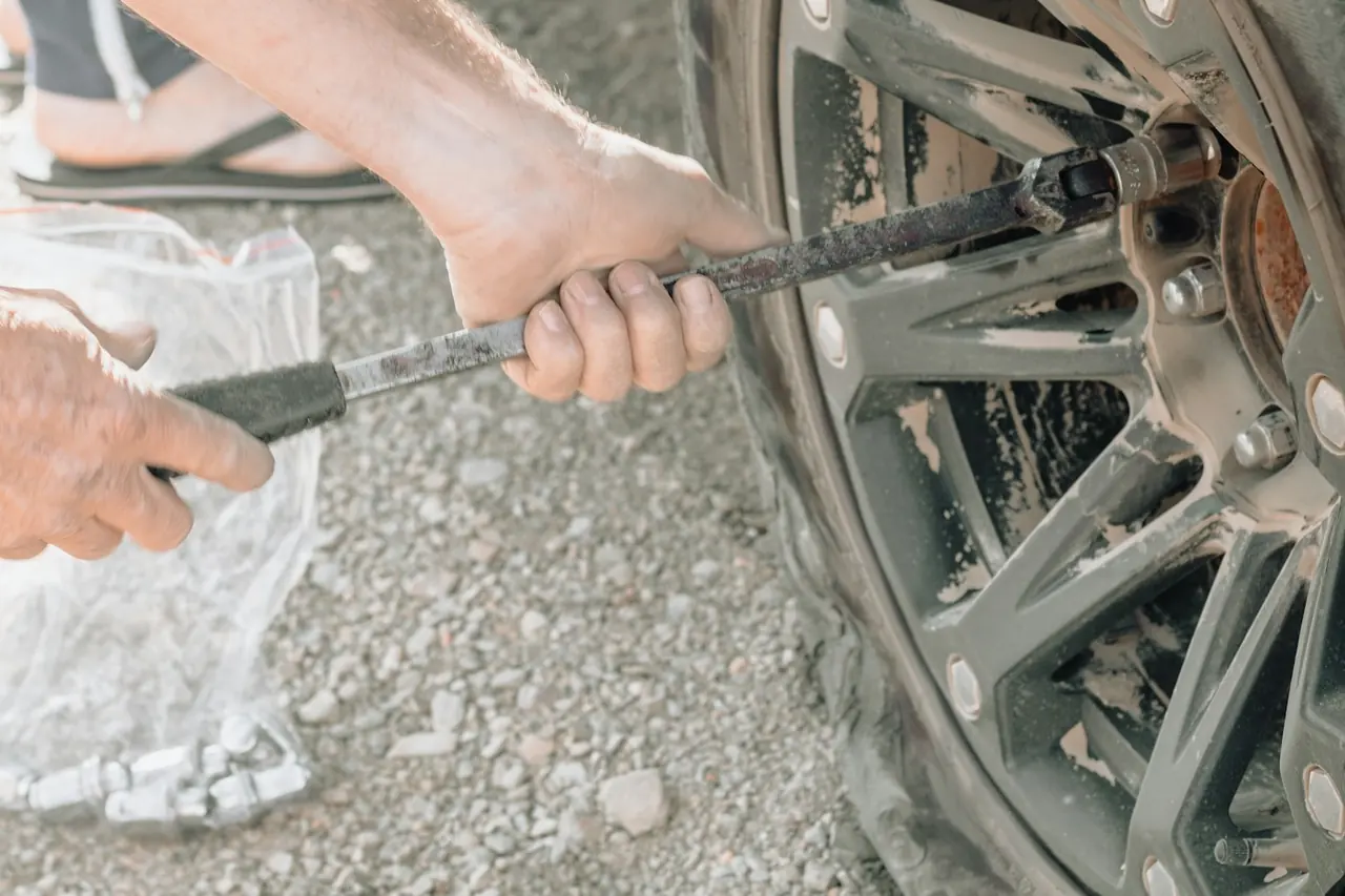 Mãos trocando o pneu furado com uma chave de roda