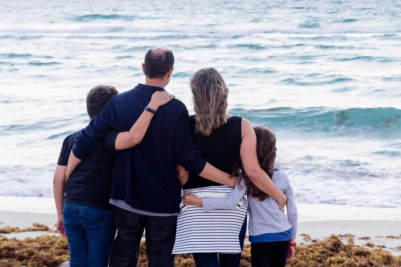Família abraçada de frente para o mar
