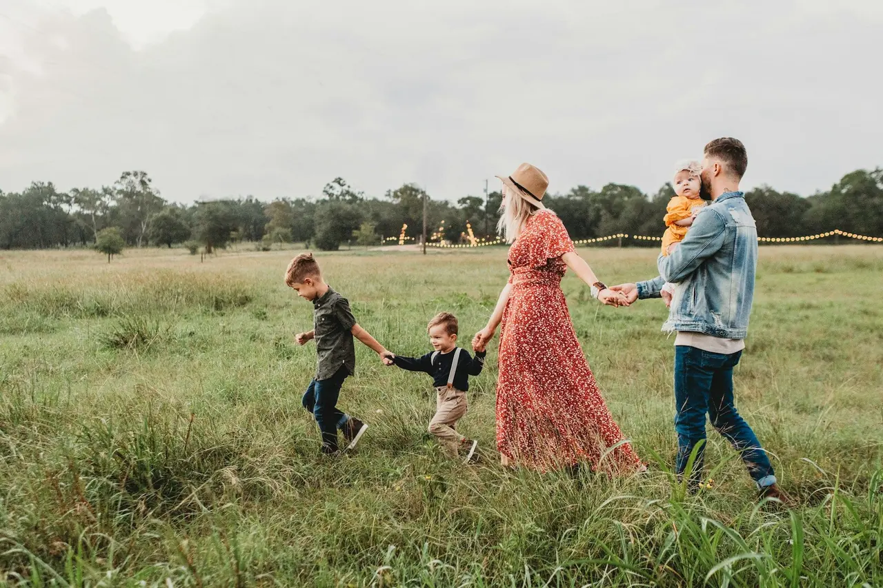 Família de mãos dadas caminhando por um campo gramado