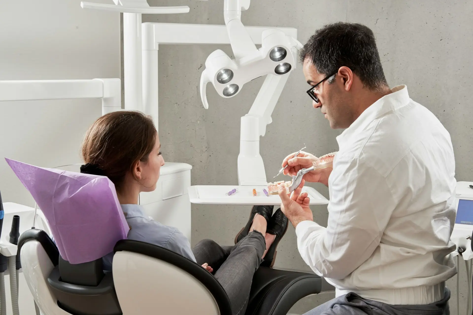 Dentista mostrando um modelo de arcada dentária a uma paciente no consultório