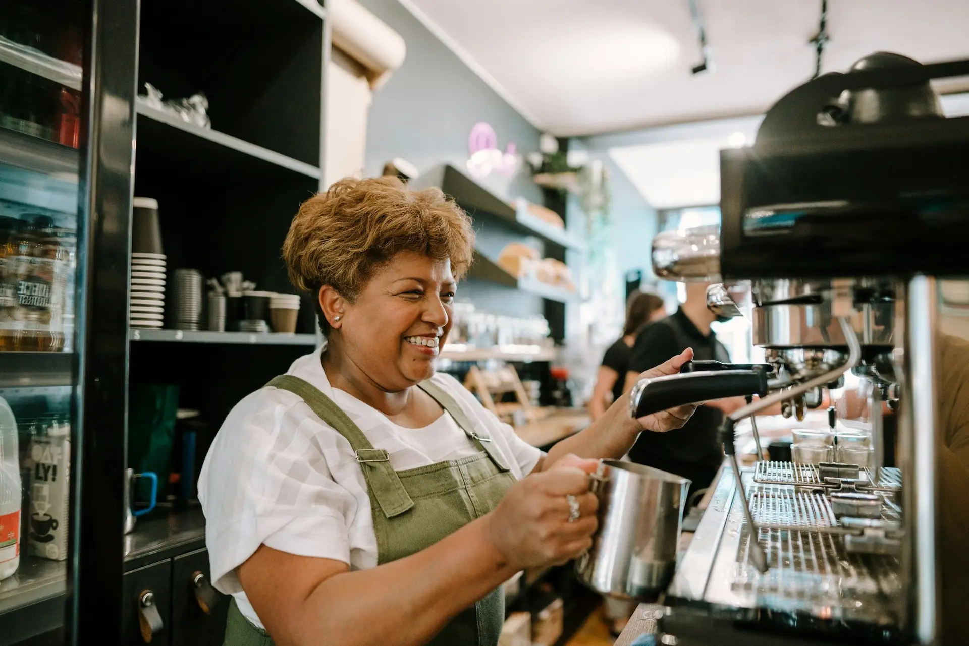 Mulher sorridente preparando café na máquina de espresso de uma cafeteria
